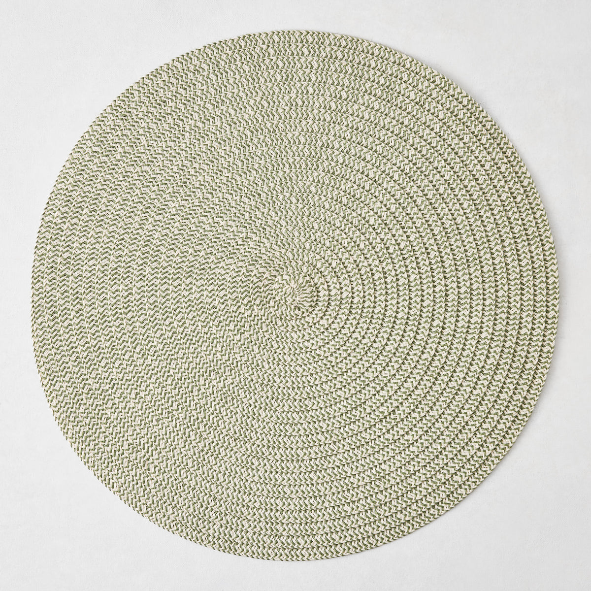 Round green and white tweed placemat with a coiled braided texture on a white background.