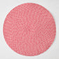 Round red and white tweed placemat with a woven spiral pattern on a white background.