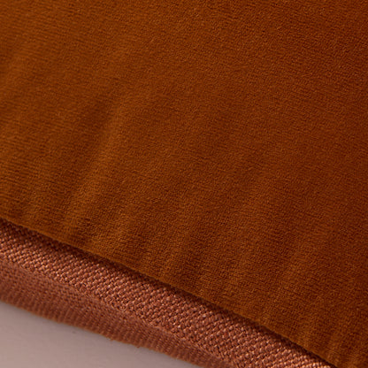 Close-up of a rust orange reversible lumbar pillow, showing velvet and linen textures.
