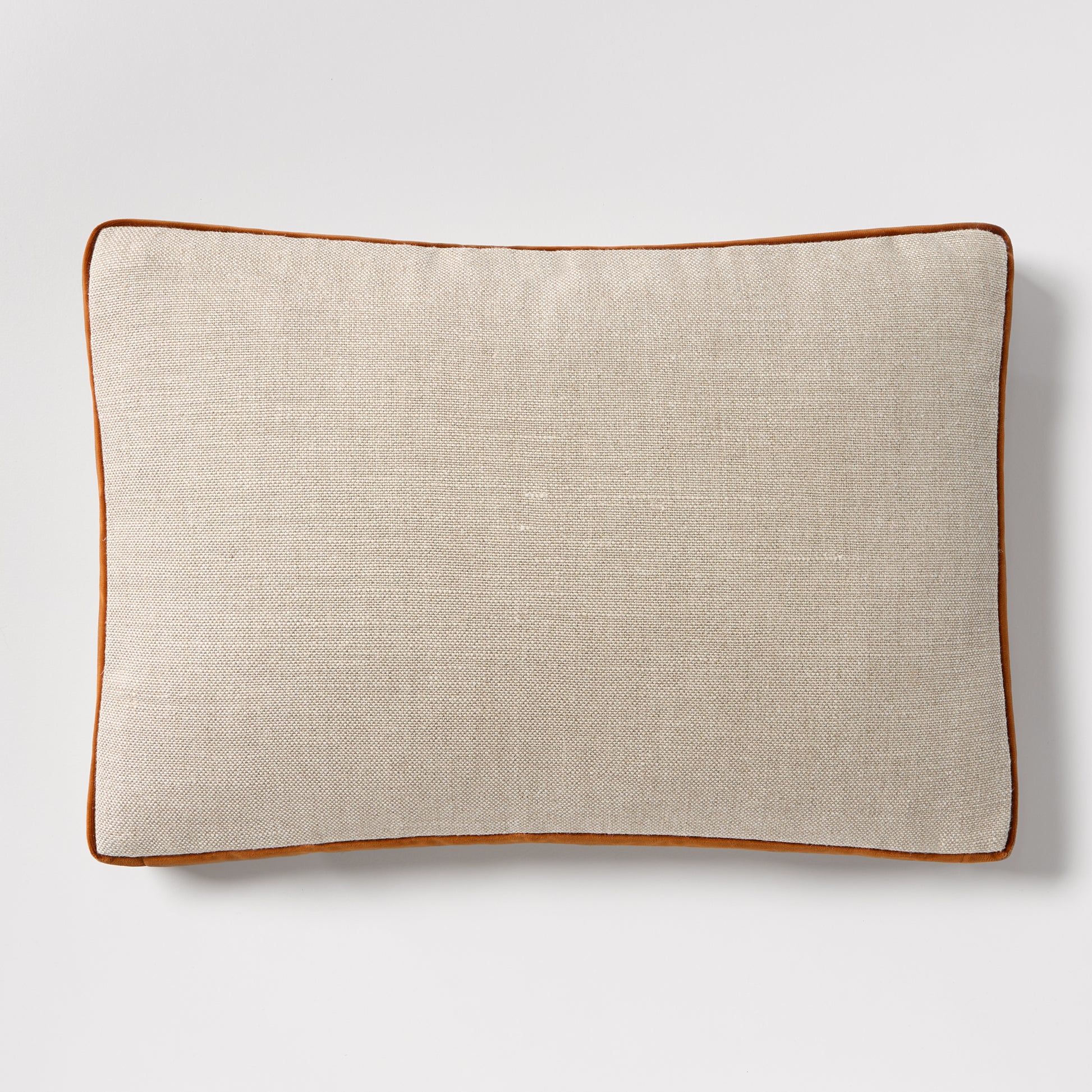 Linen lumbar pillow with rust orange velvet gusset and piping, 20"L x 14"H.