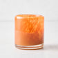 Small mouth-blown rust red glass votive candle holder with a thick base and translucent, marbled finish.