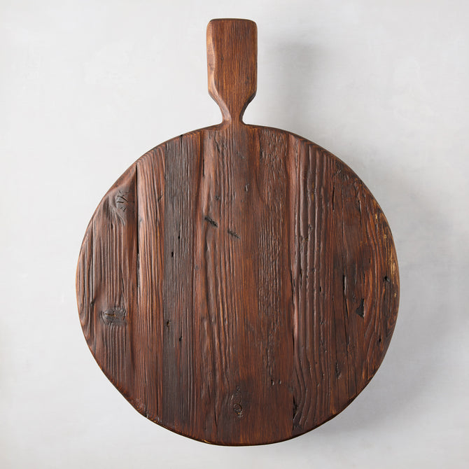 Round, dark brown, rustic European pine wood serving board with handle and footed design.