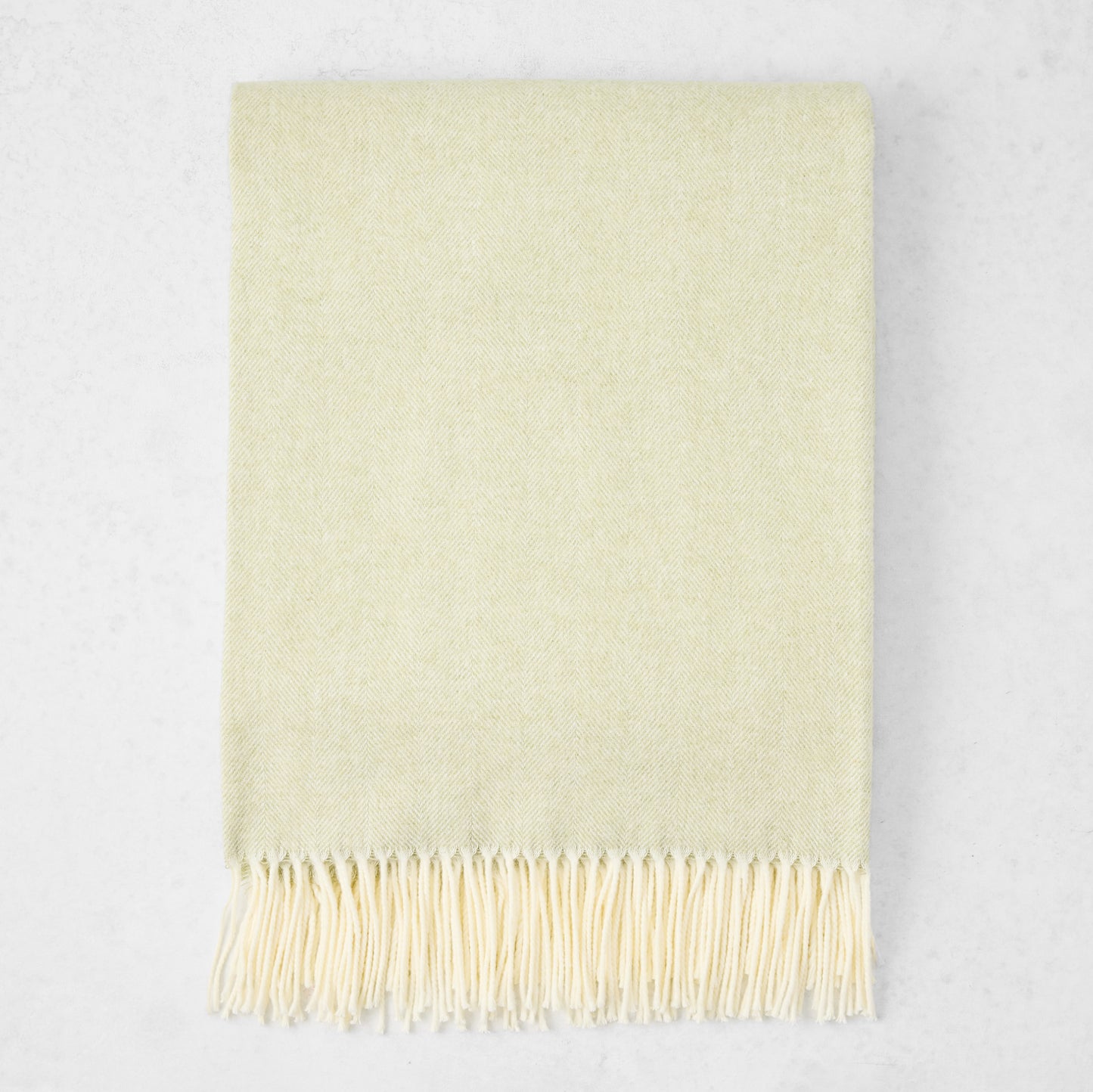 Sage Green Italian Herringbone Throw Blanket, cashmere-soft cotton-acrylic, with decorative fringe.