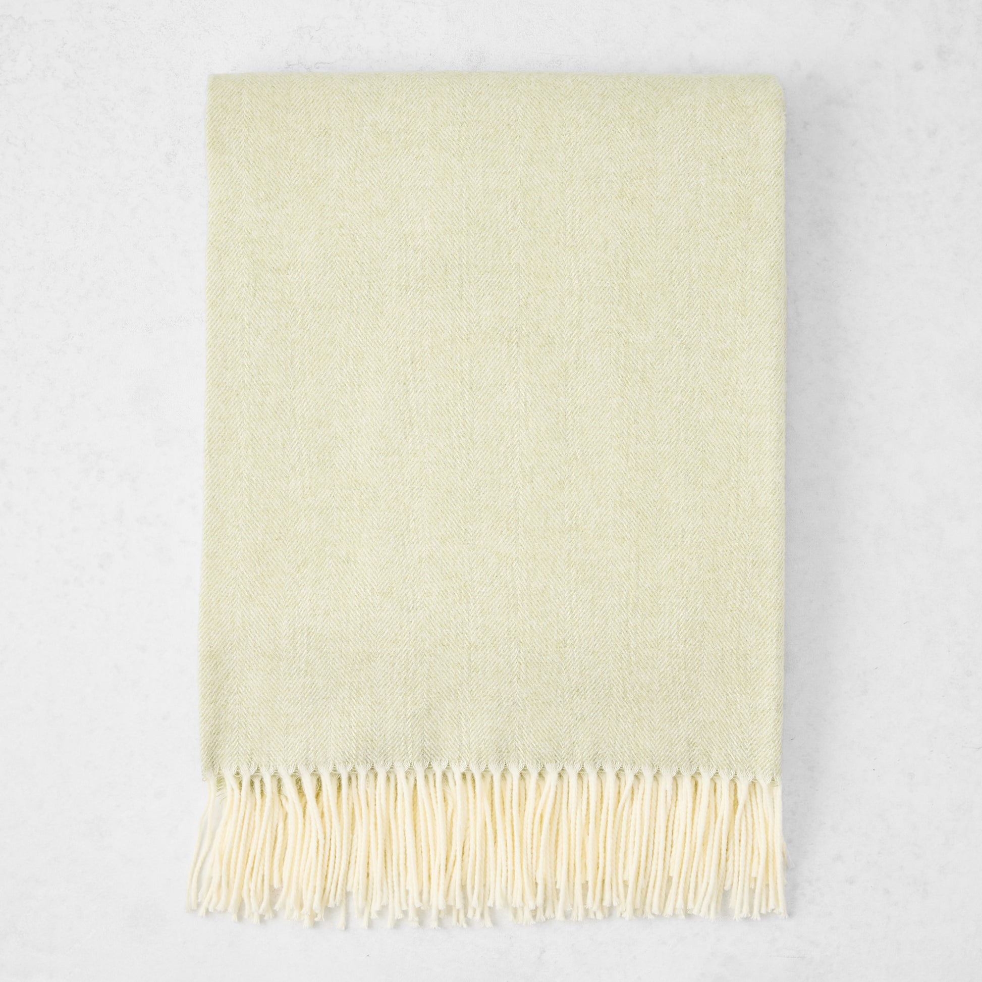 Sage Green Italian Herringbone Throw Blanket, cashmere-soft cotton-acrylic, with decorative fringe.