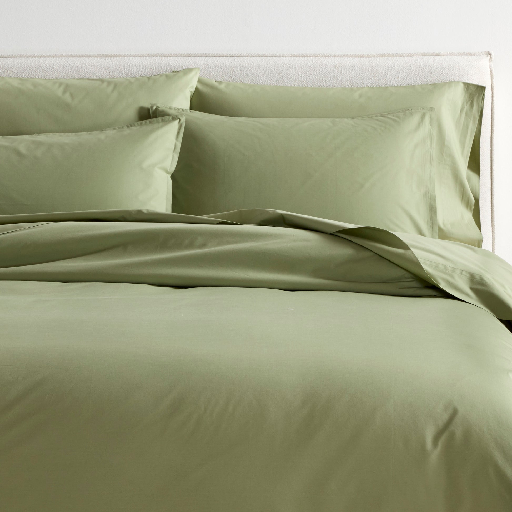 Sage green Italian percale duvet cover and two shams on a bed, showing soft, crisp cotton.