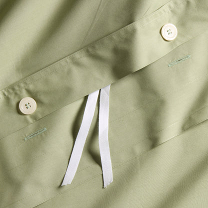 Close-up of a sage green Italian percale duvet cover with white button closures and interior ties.
