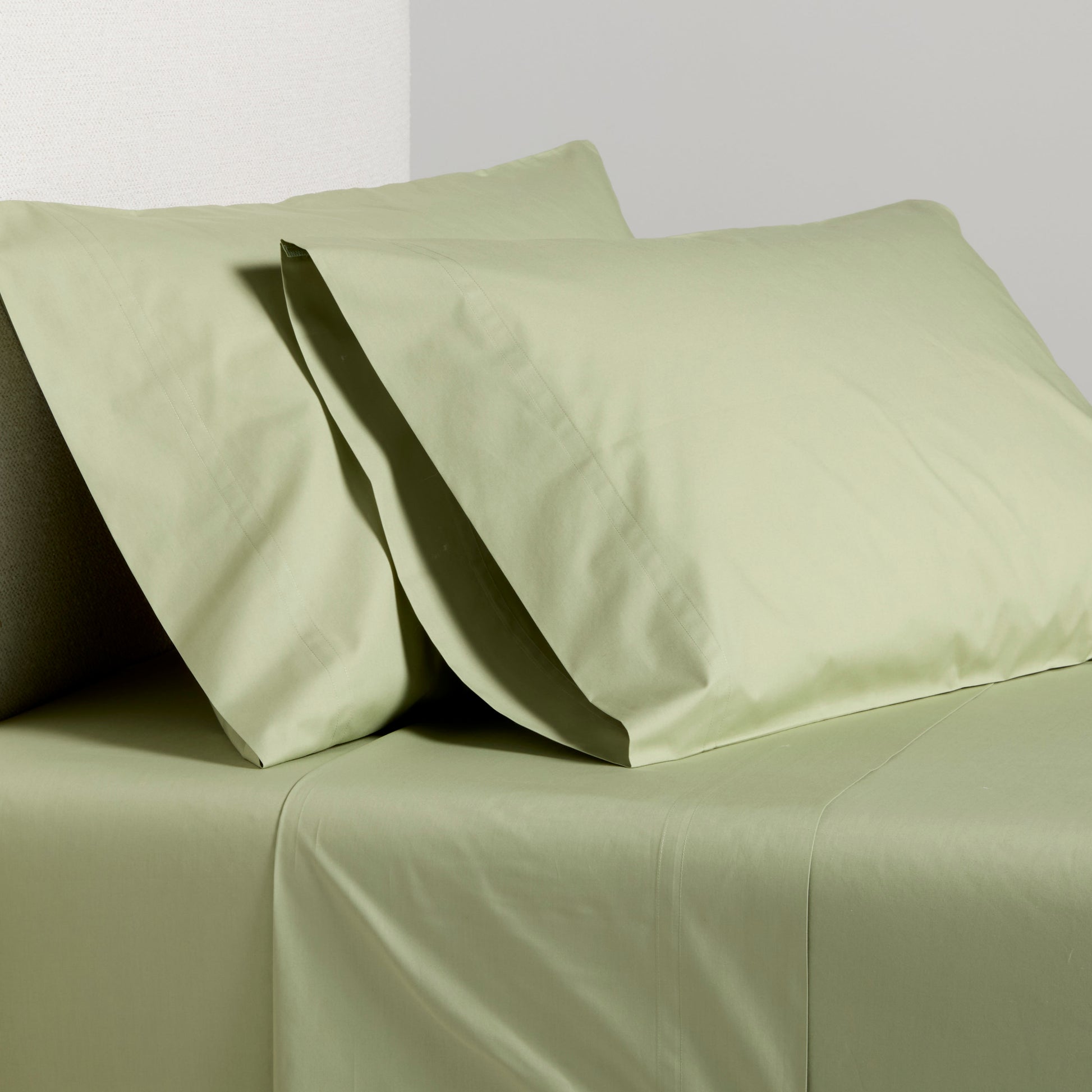 Sage green Italian percale sheet set with two pillowcases and flat sheet.