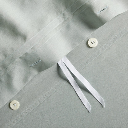 Close-up of sage green washed linen duvet cover with hidden-button closure, white buttons, and corner ties.