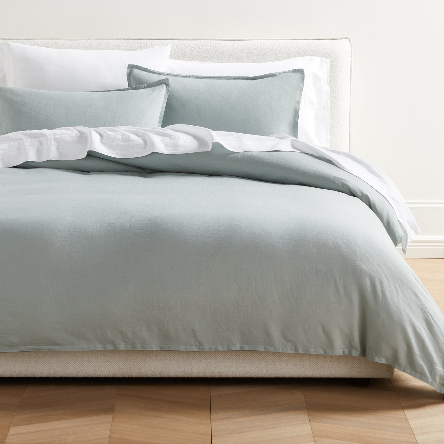 Sage Green Washed Linen Duvet Cover and two shams with 2" flange, on a bed with white sheets.