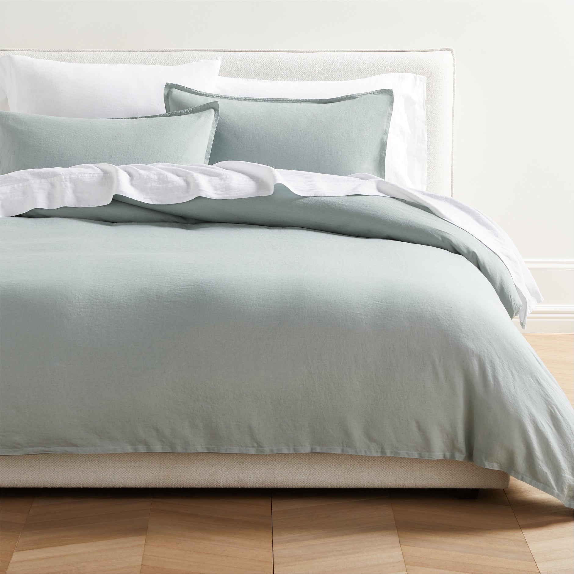 Sage Green Washed Linen Duvet Cover and two shams with 2" flange, on a bed with white sheets.