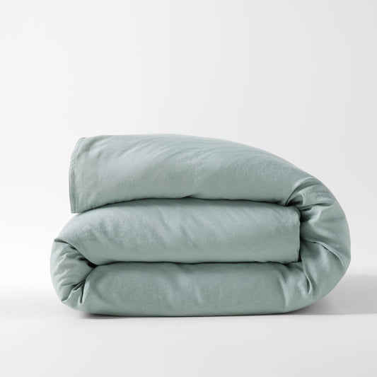 Folded sage green washed linen duvet cover, medium-weight, with a relaxed, soft texture.