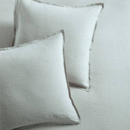 Two sage green washed linen pillow shams with 2" flange and double-needle stitching.