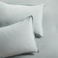 Two sage green washed linen pillow shams with a 2" flange and double-needle stitching.