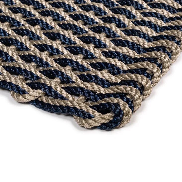 Close-up of a handwoven Sand and Navy Braided Rope Doormat with a tight, interlocking weave.