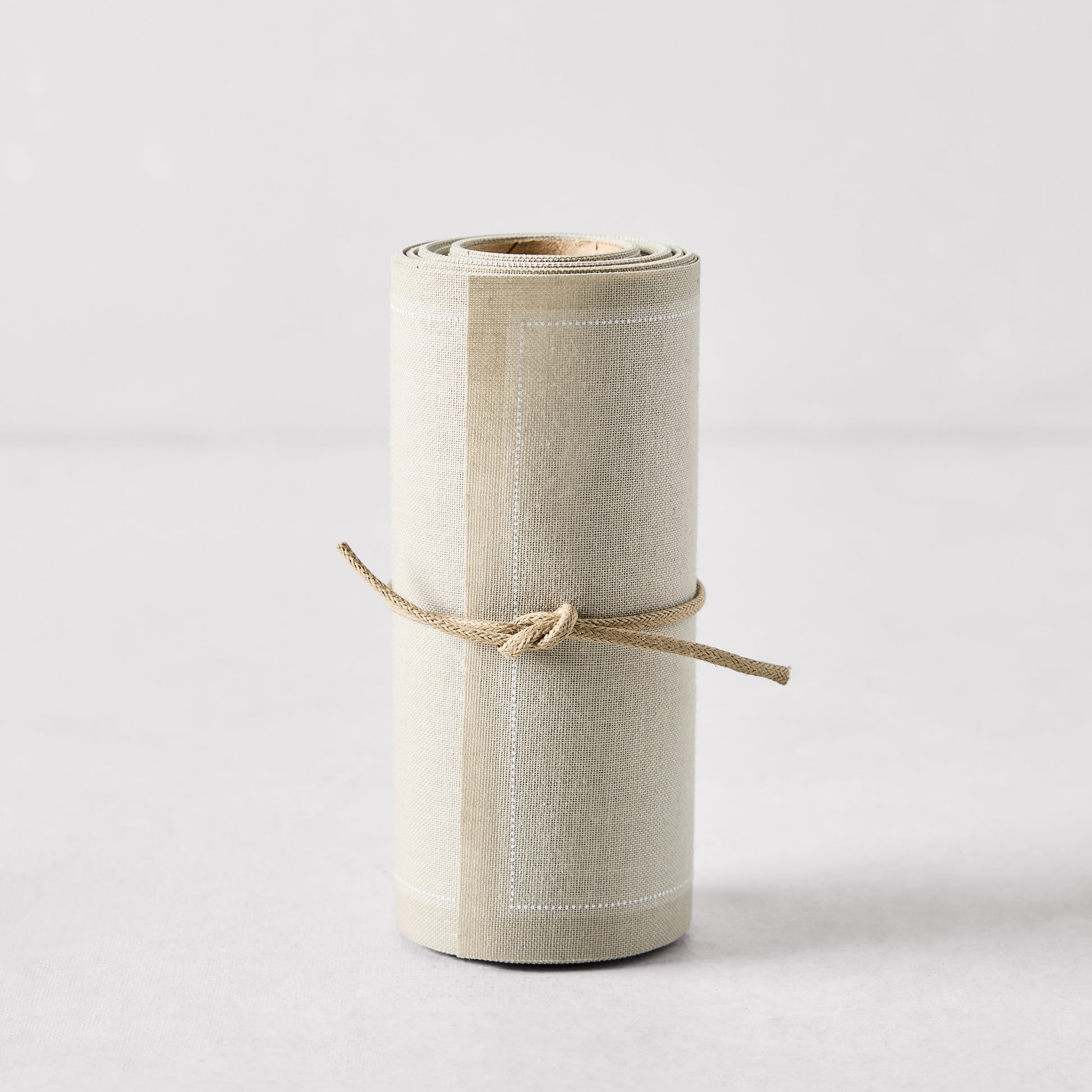 Roll of 50 sand-colored tear-off cotton cocktail napkins, tied with natural twine.