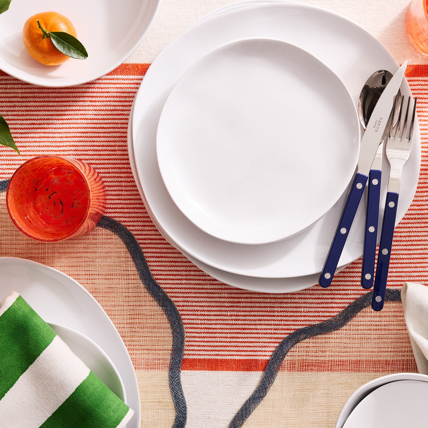 Sandia White 11" melamine dinner plate with a matte exterior and glossy interior, set on a striped tablecloth.
