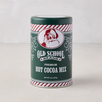 Green metal tin of Old School Brand premium hot cocoa mix featuring a vintage Santa Claus illustration and red-and-white striped trim.