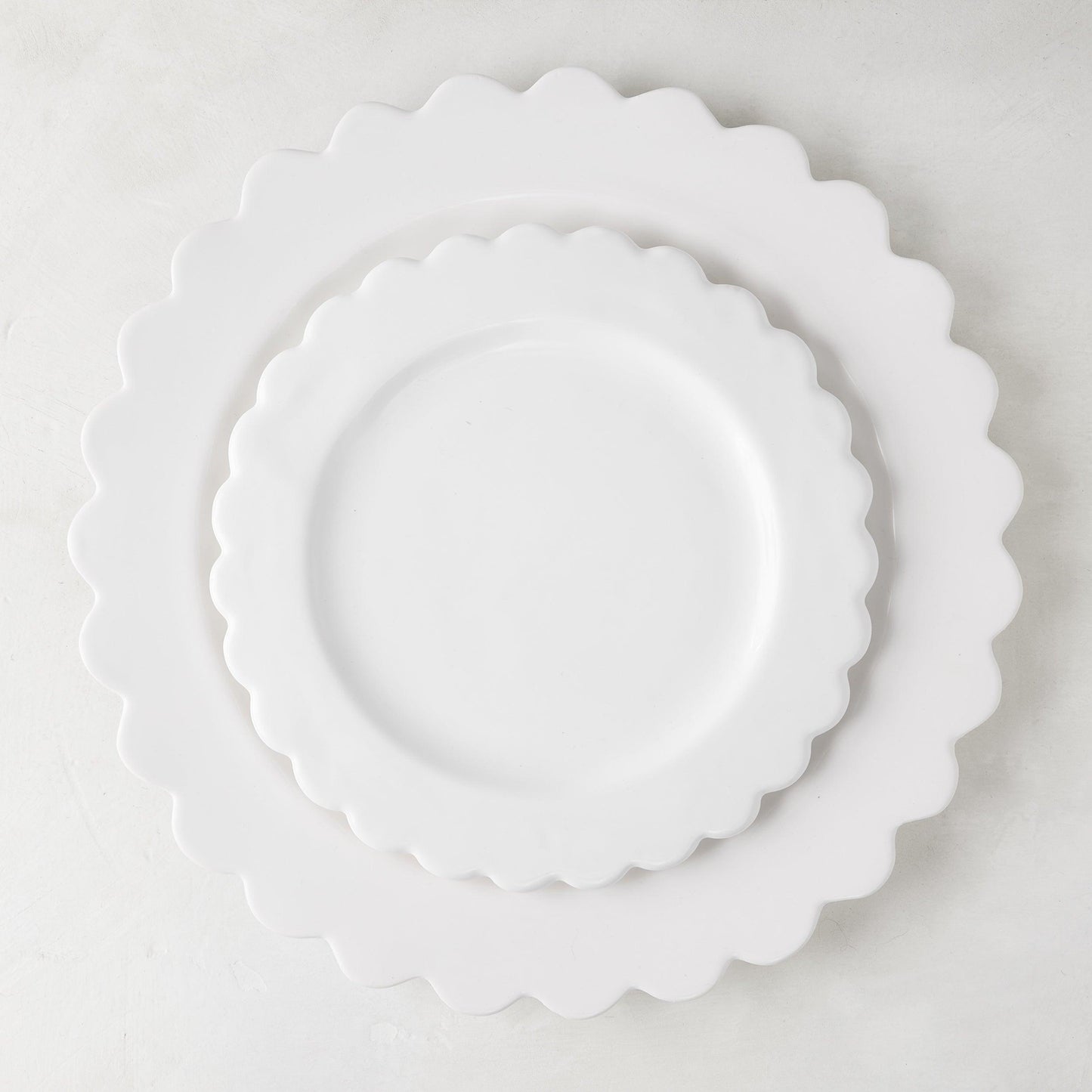 White ceramic scalloped dinner plate (12") layered with a smaller scalloped salad plate.