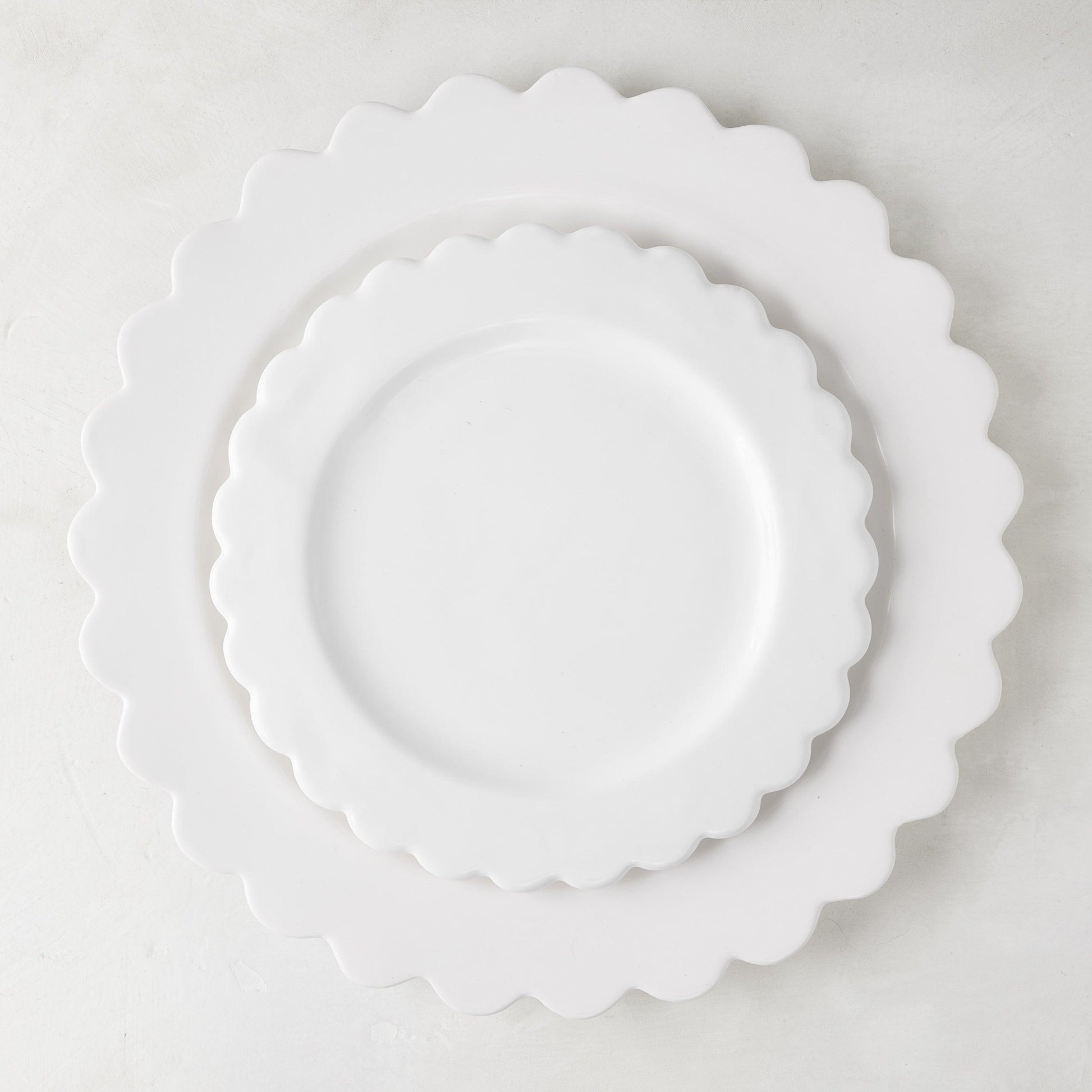 White ceramic scalloped dinner plate (12") layered with a smaller scalloped salad plate.