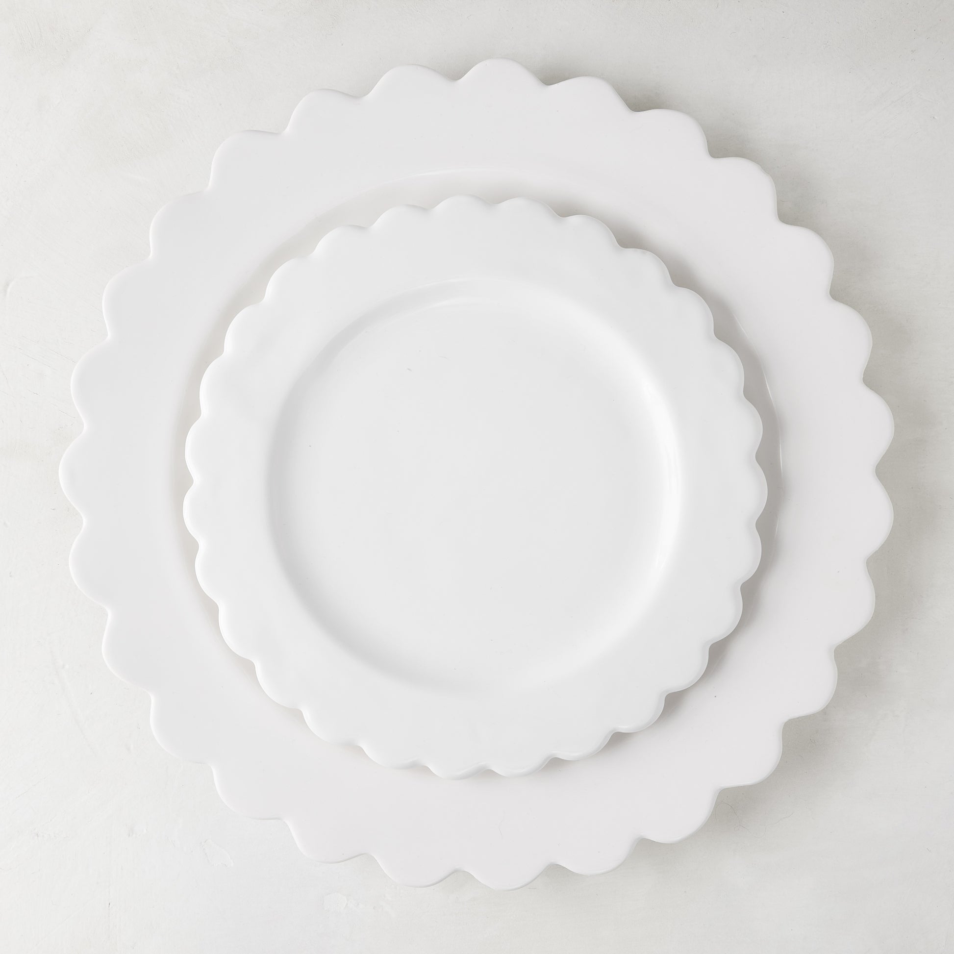 White scalloped ceramic salad plate layered on a larger scalloped charger.