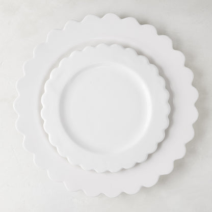White scalloped ceramic salad plate layered on a larger scalloped charger.