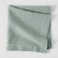 Sea Glass HG Signature hand-dyed linen napkin, folded, showing soft blue-aqua color and natural texture.