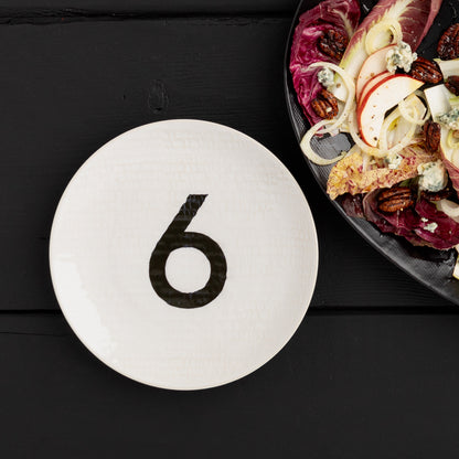 Cream ceramic salad plate with a black number 6, hammered finish, 8.5" diameter.