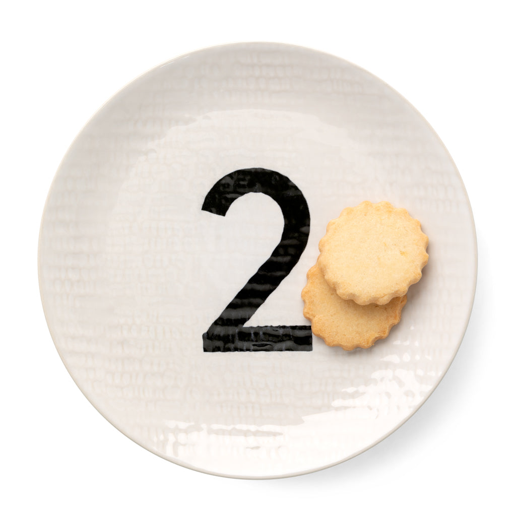 Cream ceramic salad plate with hammered finish, black number 2, and two shortbread cookies.