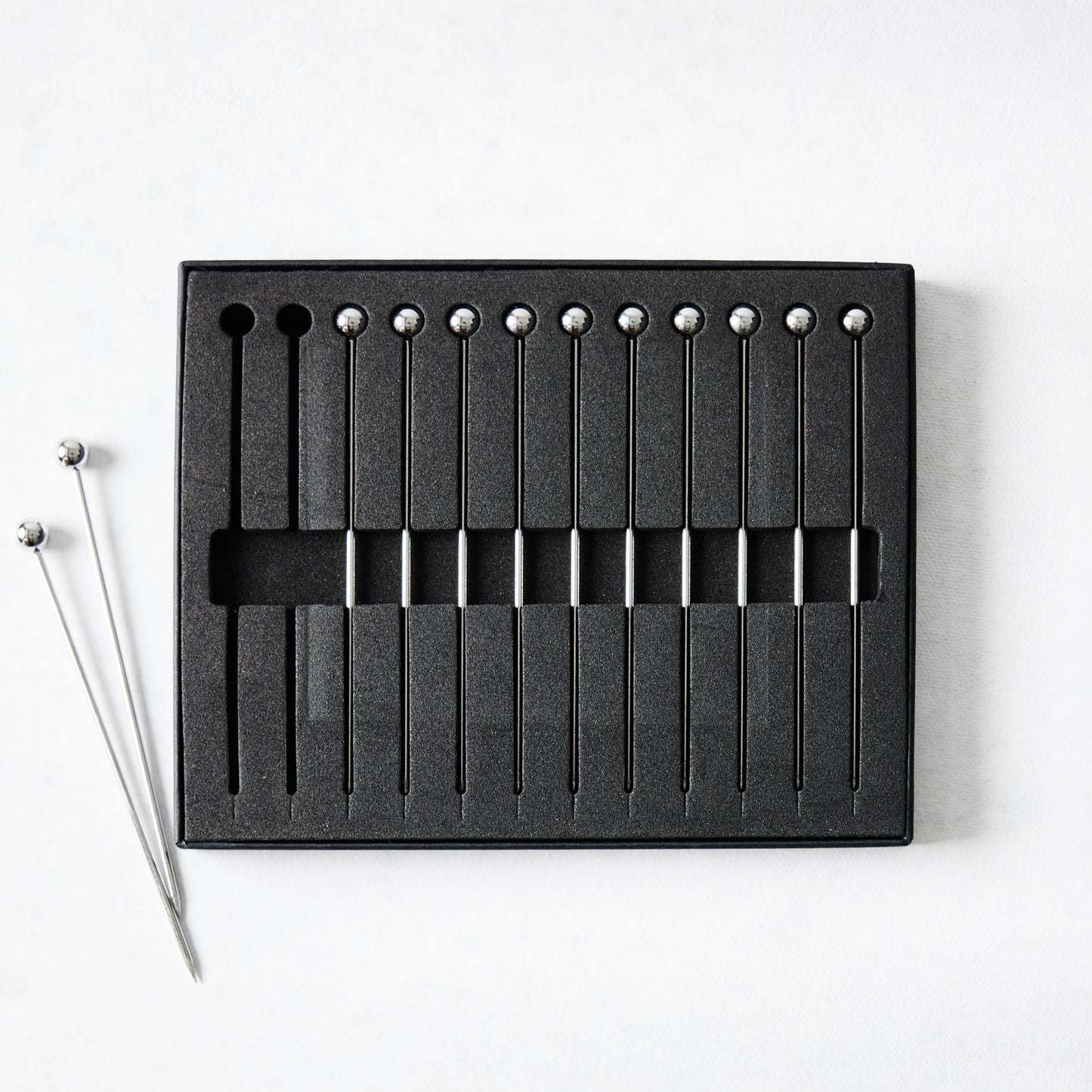 Set of 12 short 4" stainless steel cocktail picks with ball tops, in black foam packaging.