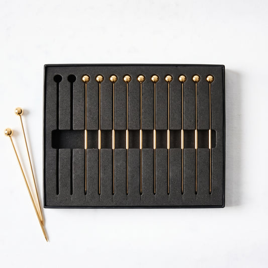 Set of 4-inch gold stainless steel cocktail picks with ball tops in a black storage box.