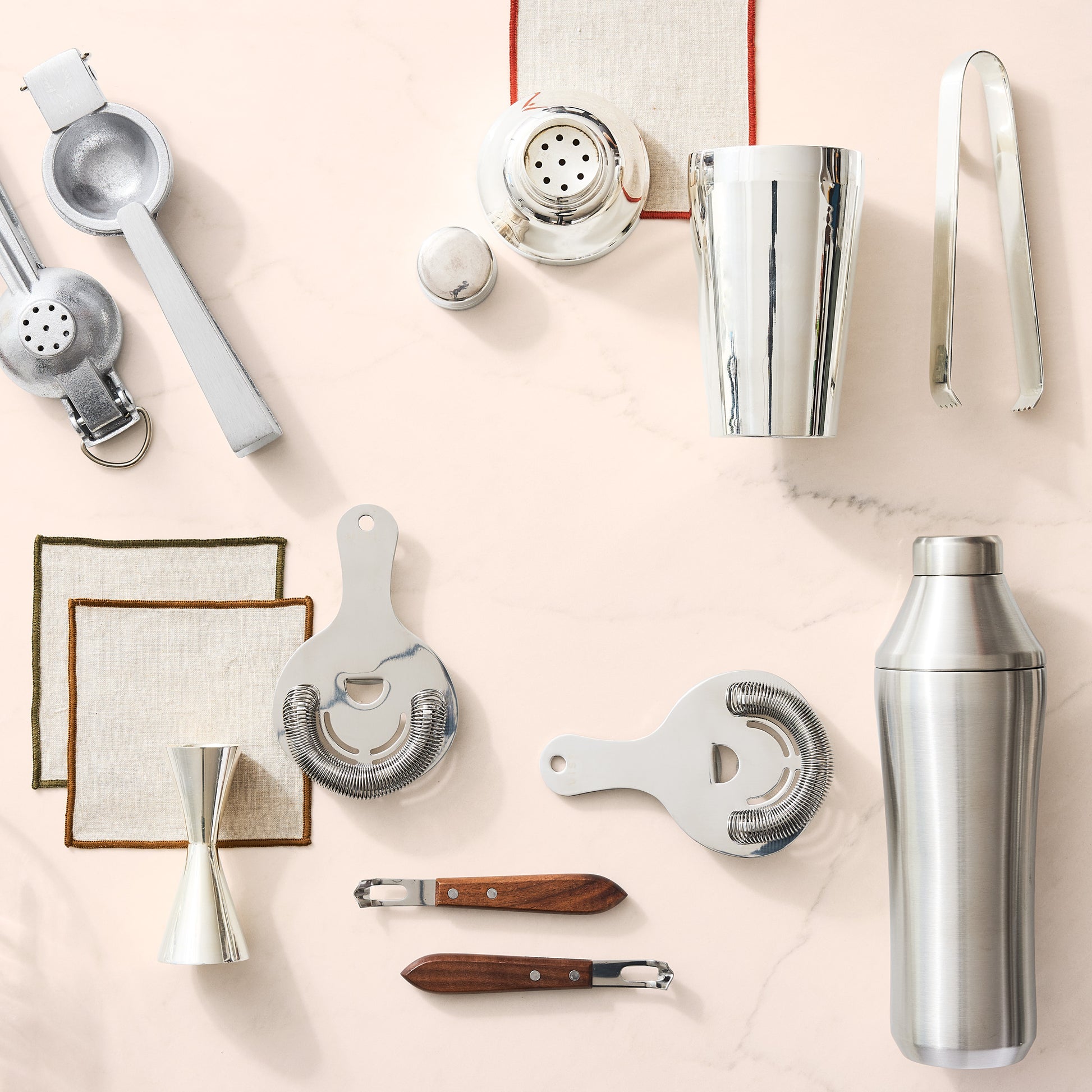 Silver HG Silverplate Ice Tongs, a key bar tool, shown with other cocktail accessories on a light marble surface.