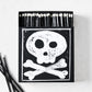 Black box of oversized matches featuring a white skull and crossbones design with black matchsticks and white tips.