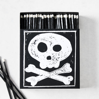 Black box of oversized matches featuring a white skull and crossbones design with black matchsticks and white tips.