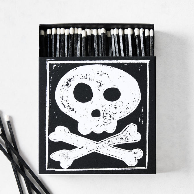 Black box of oversized matches featuring a white skull and crossbones design with black matchsticks and white tips.