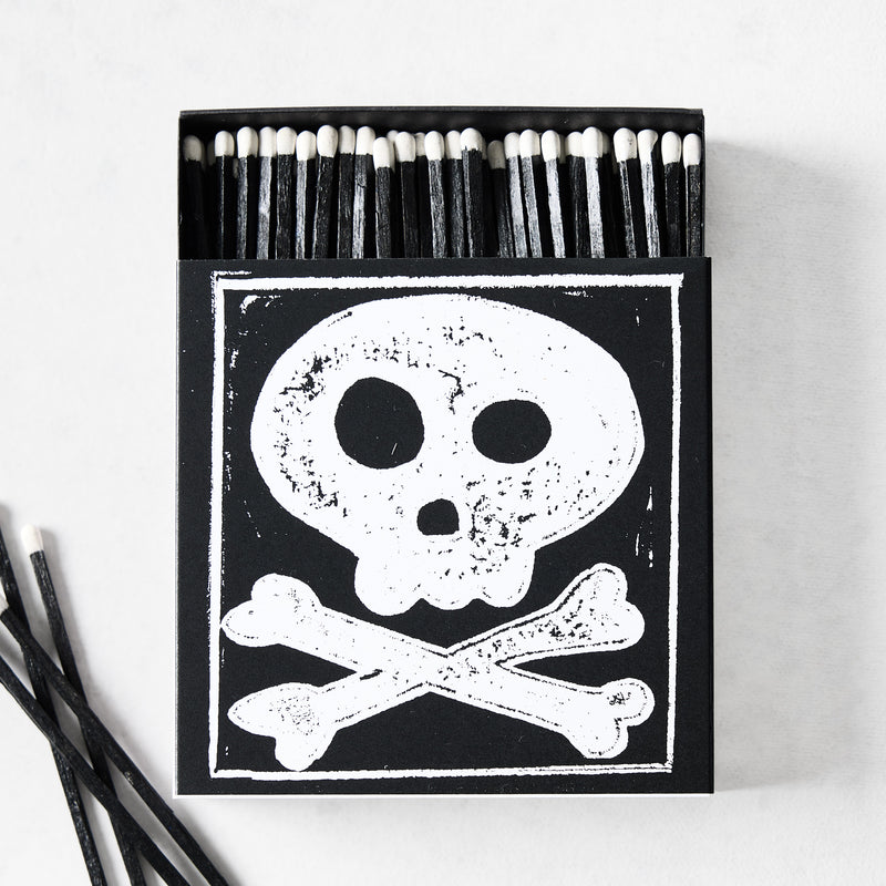 Black box of oversized matches featuring a white skull and crossbones design with black matchsticks and white tips.