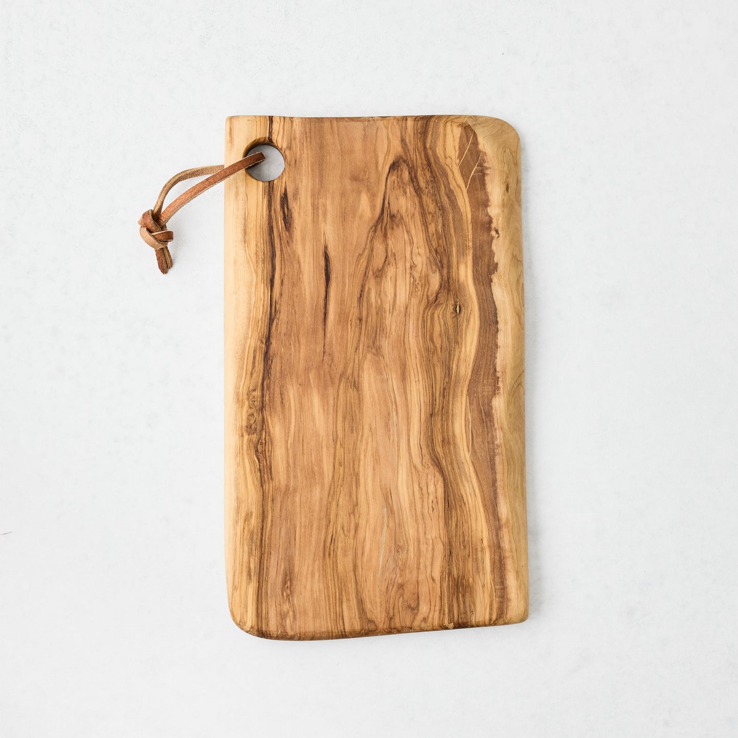 Artisan olive wood rectangular serve board with natural grain and leather hanging cord.