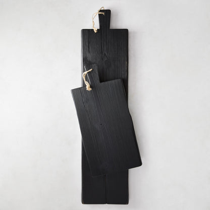Two black reclaimed wood serving planks, one long and one shorter, with rope hangers.