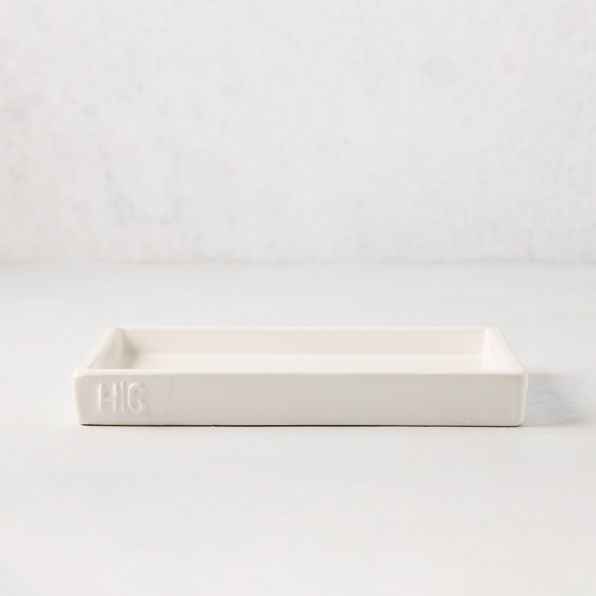 White ceramic rectangular tray with an understated lip and "HG" monogram.