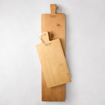 Two Hudson Grace light brown European pine wood serving planks, one large and one small, with rope handles.