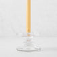 Small clear glass single candleholder with ridges, holding a beige taper candle.