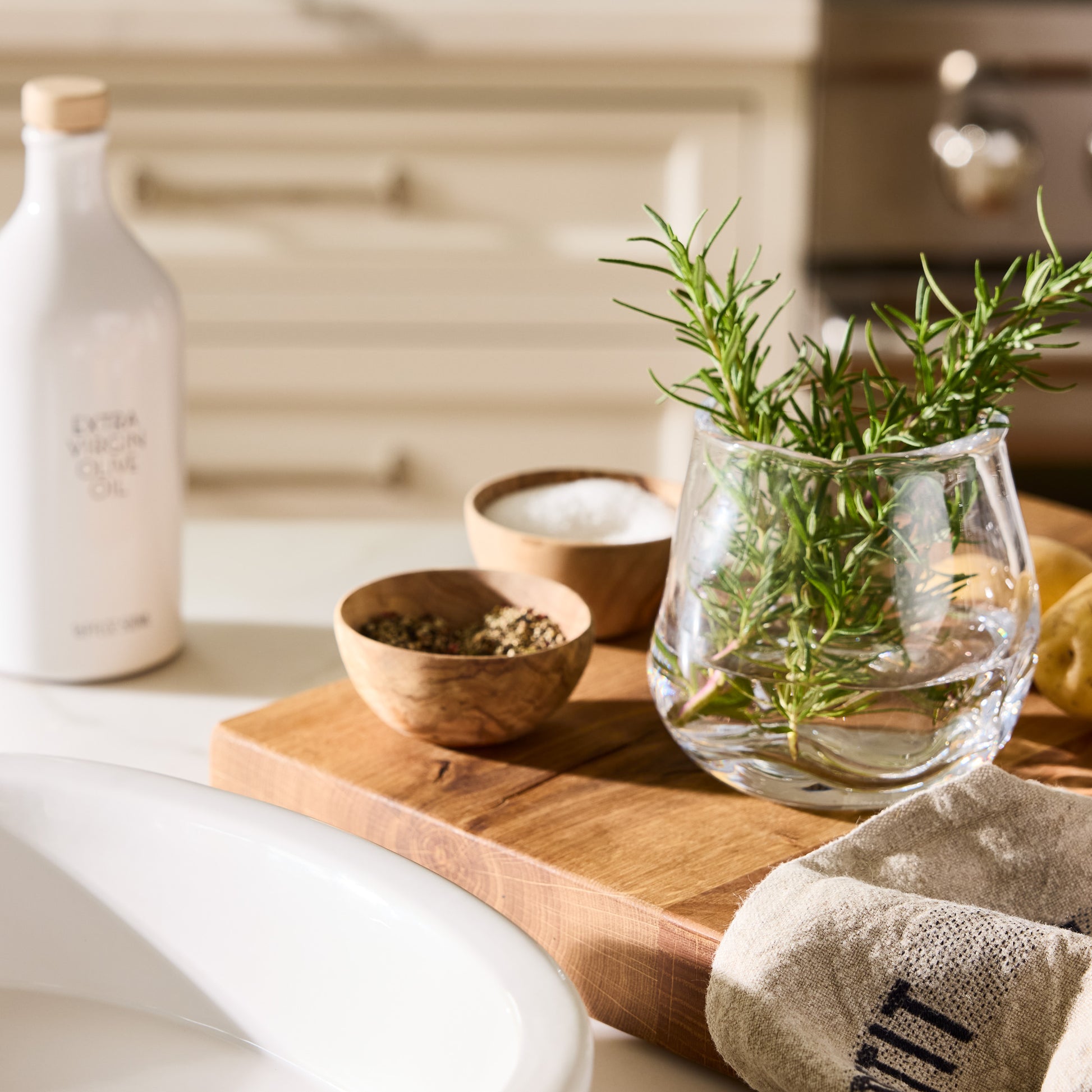 Small Mia Scissor-Cut Round Vase, clear mouth-blown glass with rosemary, on a wooden board with spices.