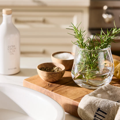 Small Mia Scissor-Cut Round Vase, clear mouth-blown glass with rosemary, on a wooden board with spices.
