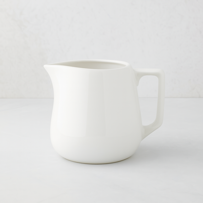 Small white ceramic milk pitcher with a simple, artisanal design.