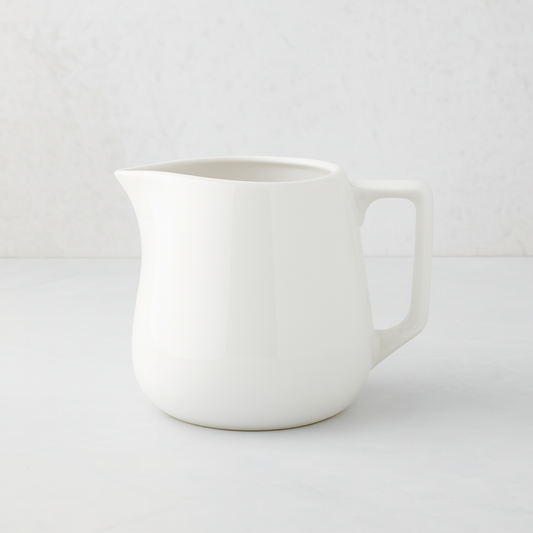 Small white ceramic milk pitcher with a simple, artisanal design.