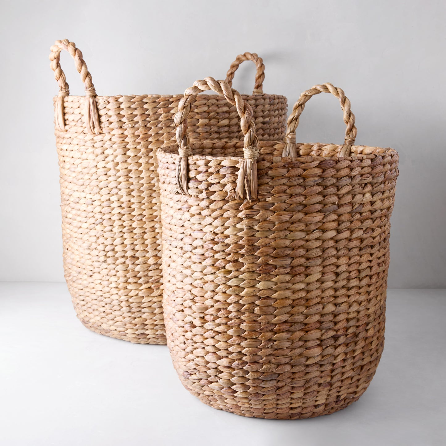 Two Montauk Woven Hyacinth Round Baskets, one small and one large, with braided handles.