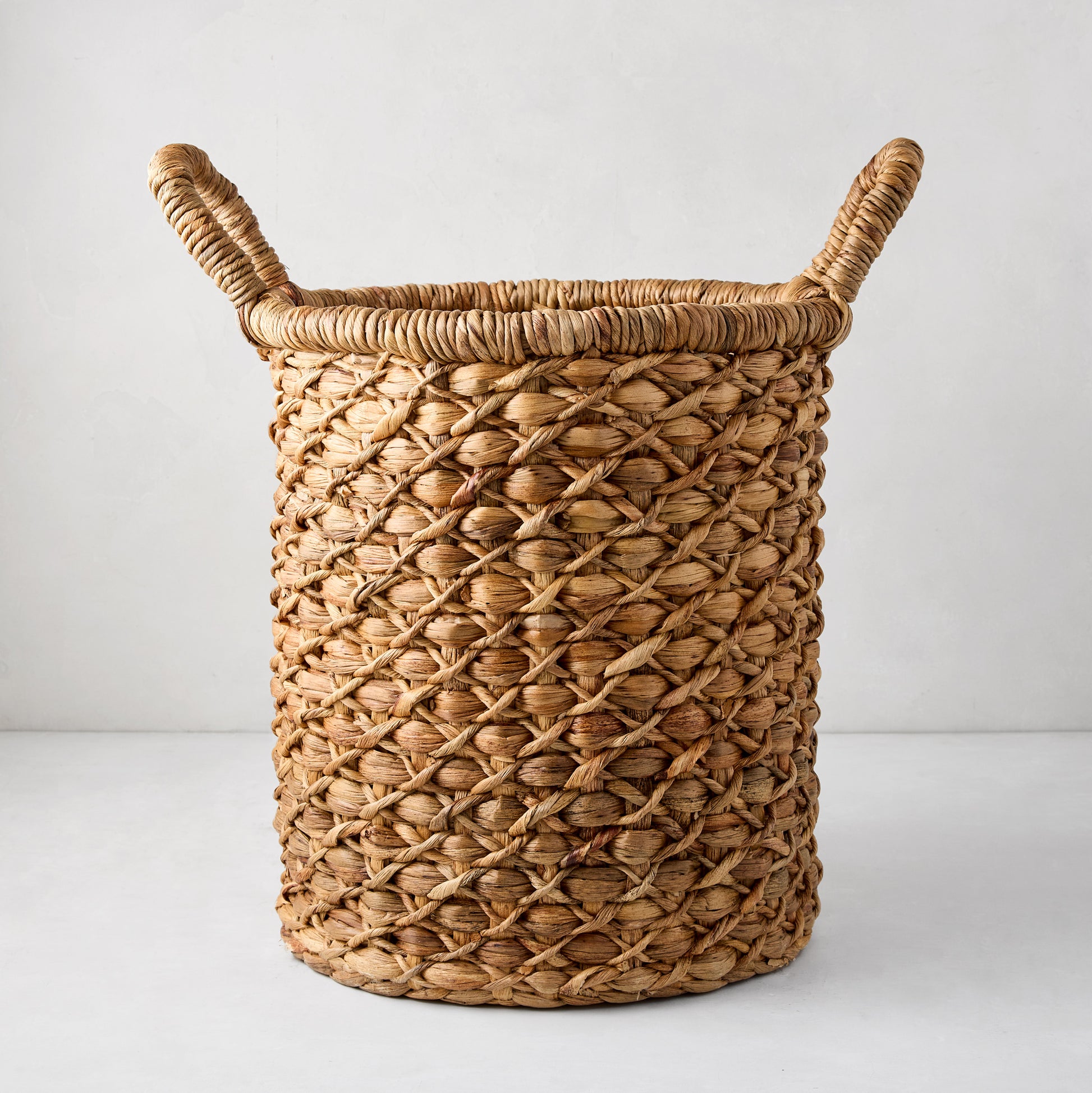 Handwoven round hyacinth leaves basket with natural brown tone and two top handles.