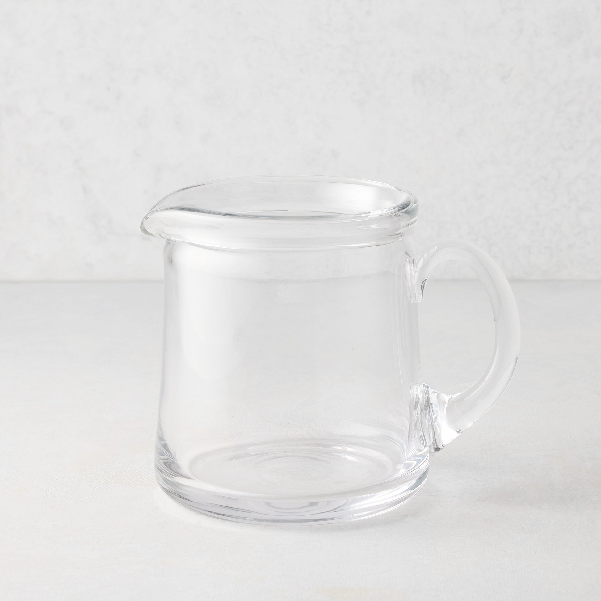 Small Oxford clear glass pitcher with a hand-molded rim and handle.