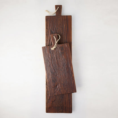 Two dark brown, rustic European pine wood serving planks with rope straps, one smaller, on a white background.
