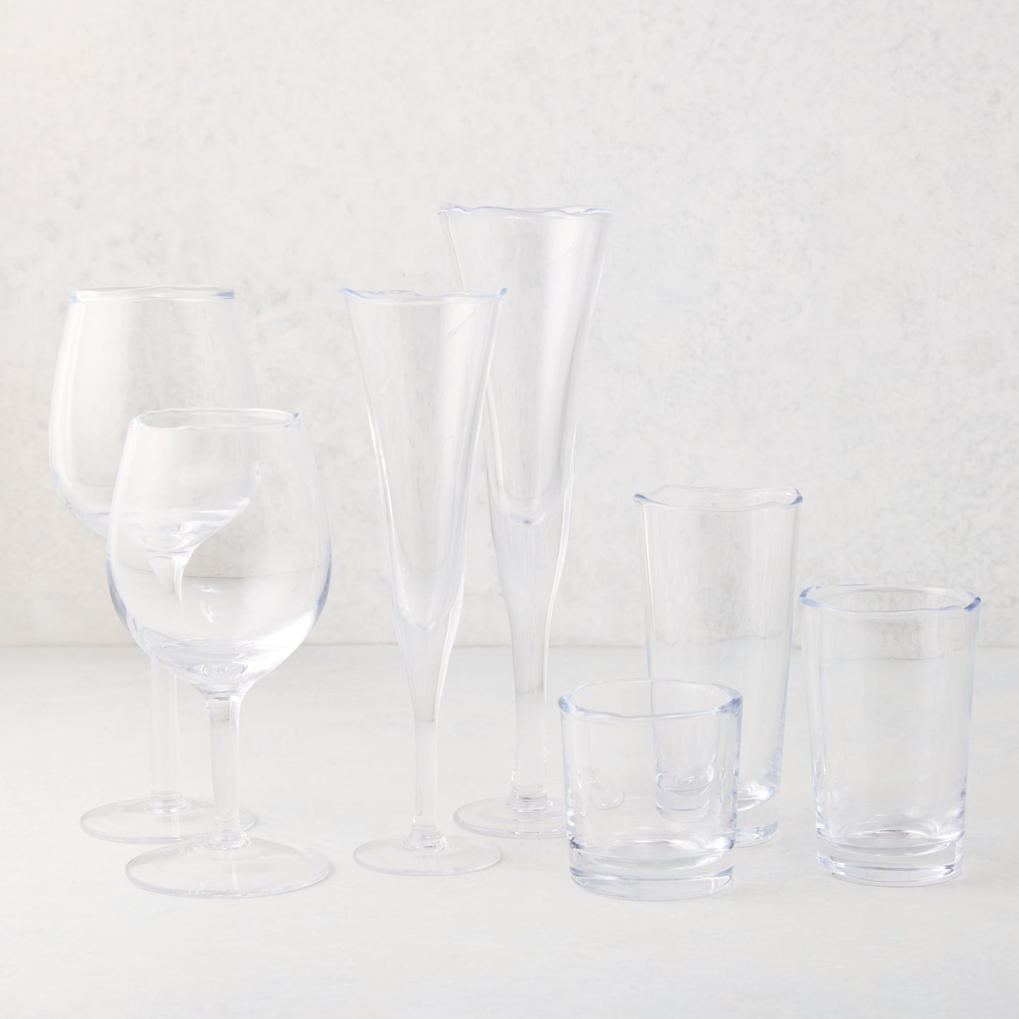 Clear, thick, scissor-cut glass champagne flute with rippled rim, alongside other drinkware.