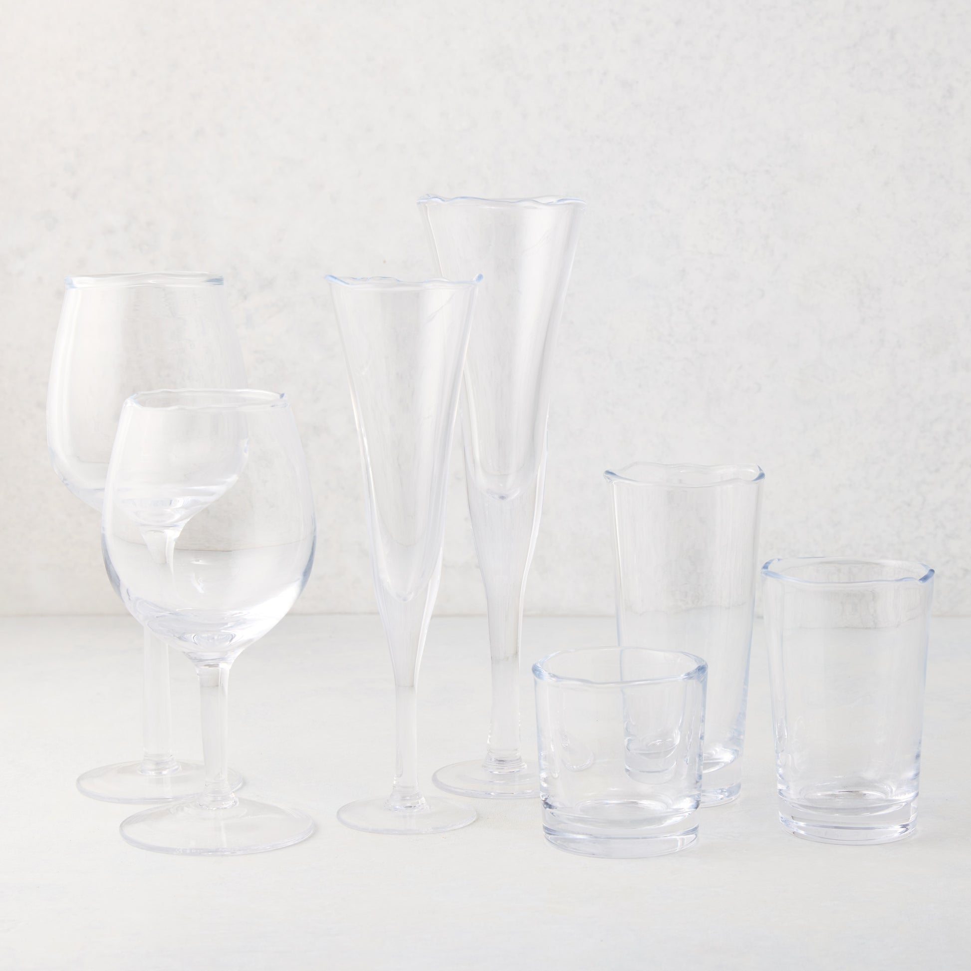 Clear, thick, scissor-cut glass champagne flute with rippled rim, alongside other drinkware.